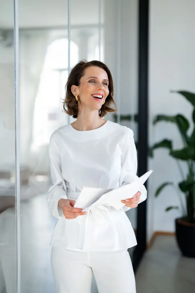 Event Moderator Franziska Zimmermann in weiß gekleidet in einem Büro stehend mit Aufzeichnungen zu einer Moderation in der Hand