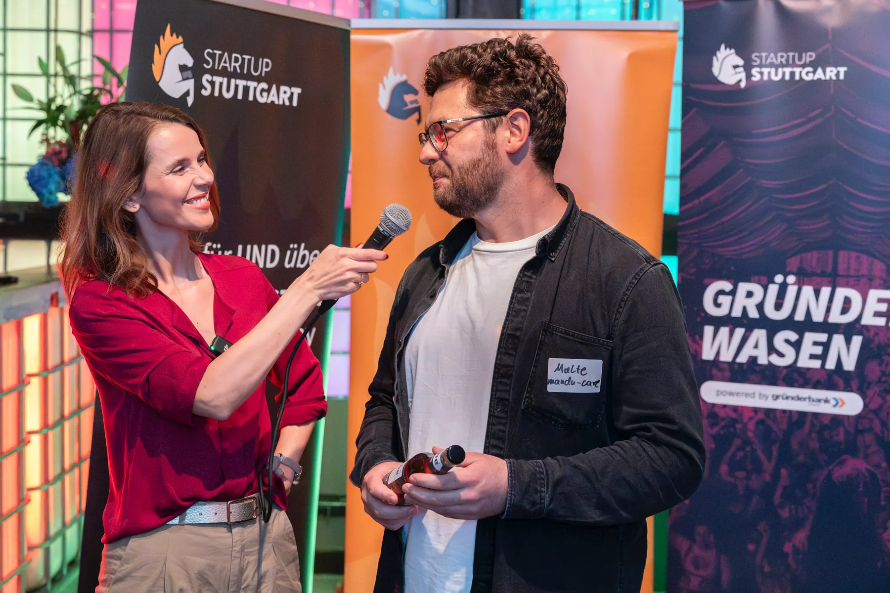 Event Moderatorin Franziska Zimmermann während eines Interviews, im Hintergrund Rollups von Startup Stuttgart