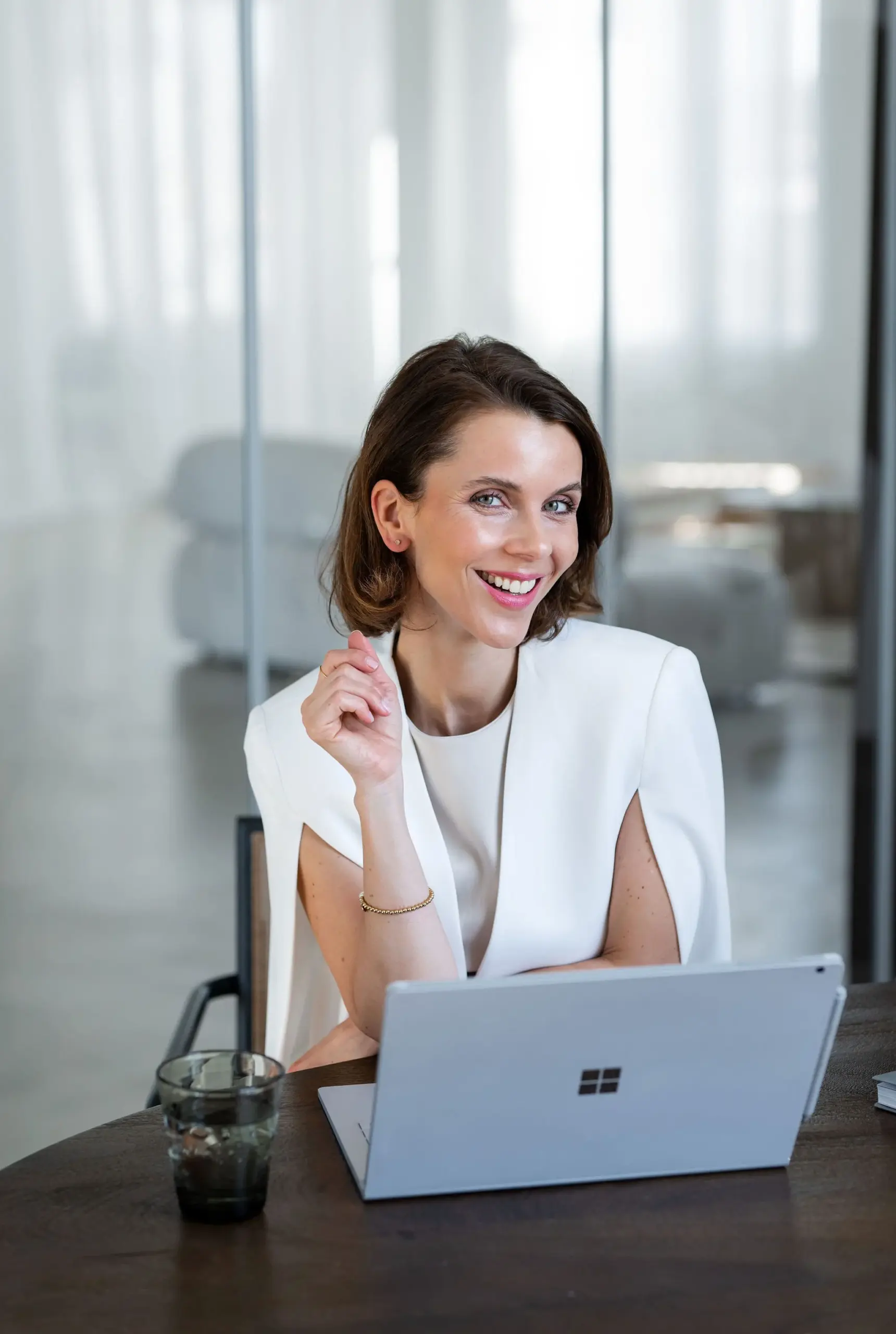 Sales Trainer Franziska Zimmermann sitzt an einem Tisch mit dem Laptop vor sich und lächelt in die Kamera
