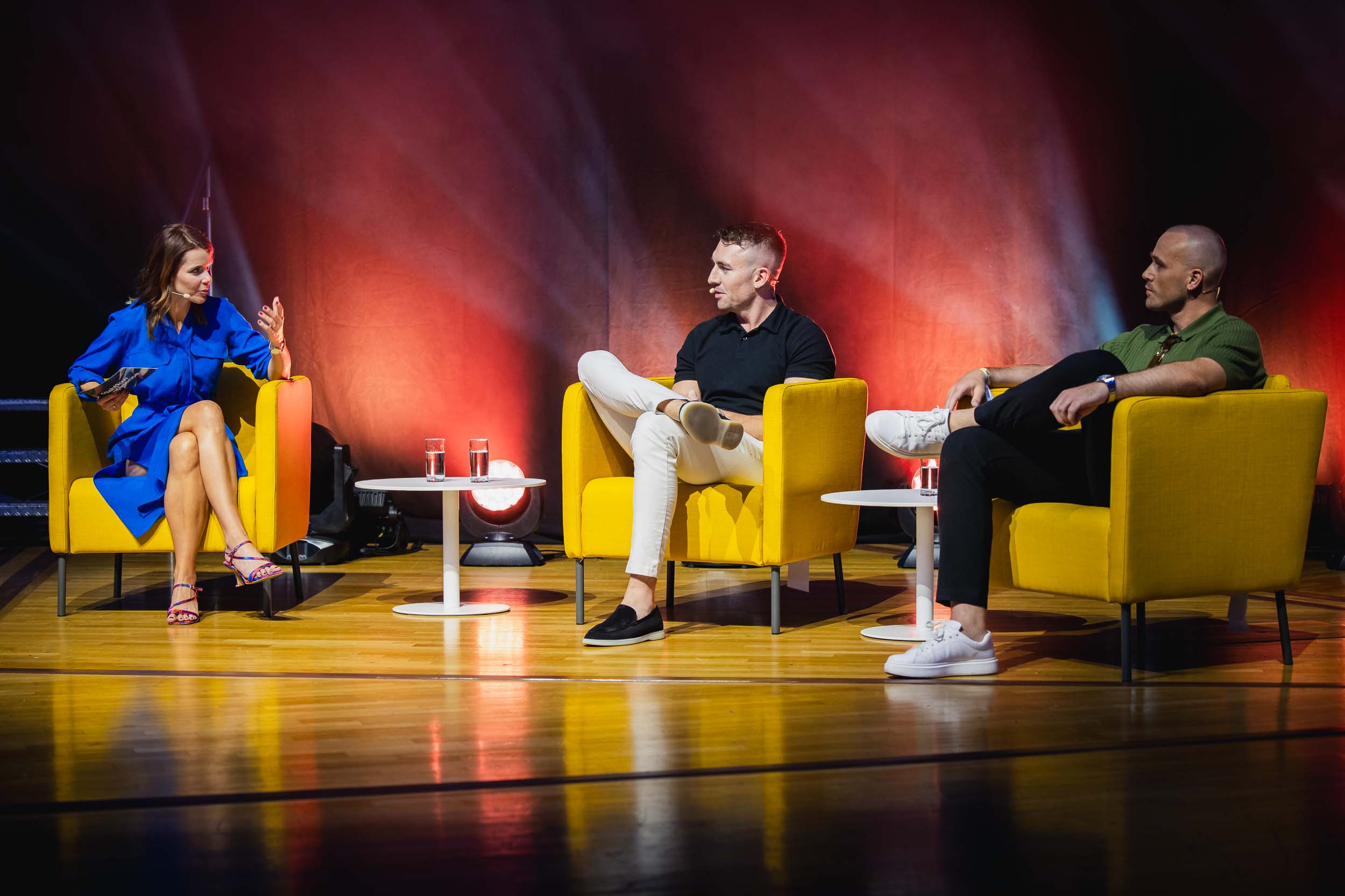 Panelmoderatorin Franziska Zimmermann in einem blauen Kleid auf einem gelben Sessel im Interview auf einer Pabeldiskussion zum Thema Finance und Investments