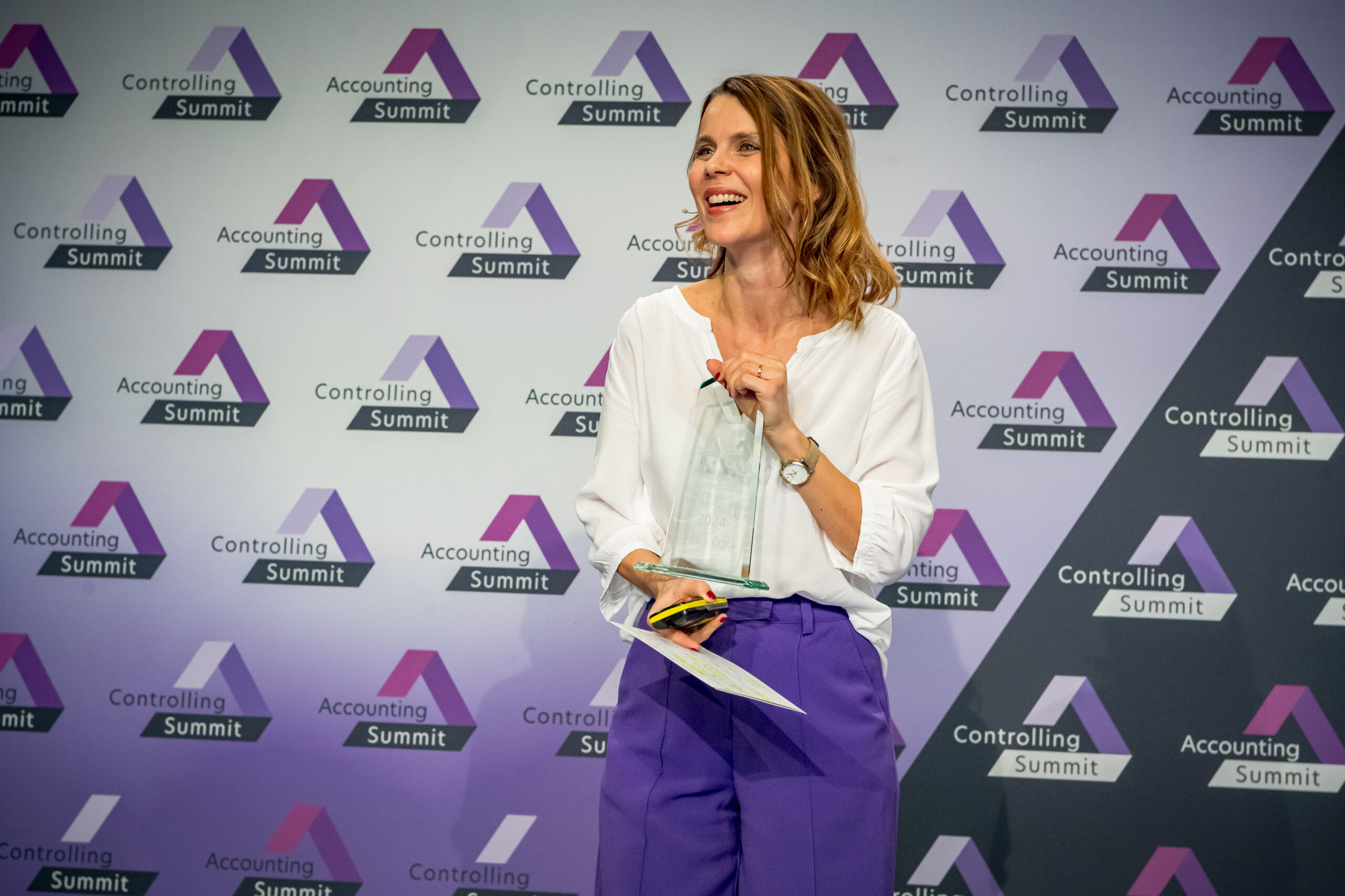 Moderatorin Düsseldorf Franziska Zimmermann beim Accounting & Controlling Summit im Areal Böhler – lachend auf der Bühne bei einer Awardverleihung